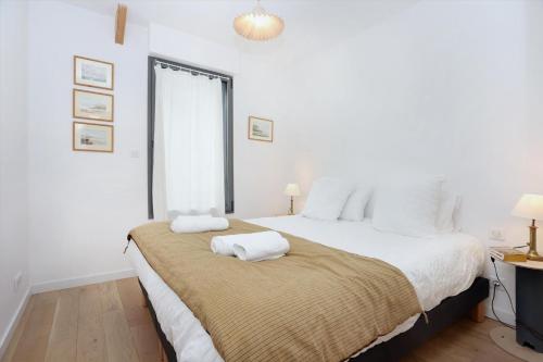 - une chambre blanche avec un grand lit et 2 serviettes dans l'établissement Bonne rencontre, à Saint-Malo