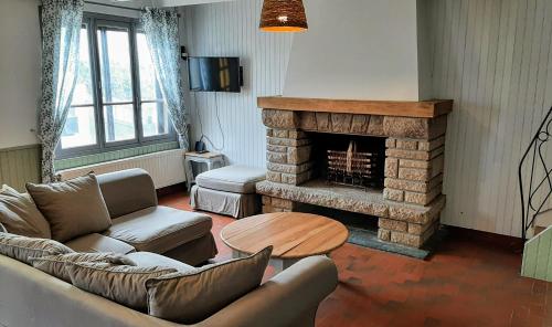 un salon avec un canapé et une cheminée dans l'établissement Maison cosy & jardin privé Plages à 5 min, à Tourville-sur-Sienne