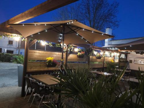 a patio with tables and chairs under an umbrella at Logis Hôtel Des Acacias Lille Neuville en Ferrain, Restaurant l'Acacias Gourmand in Neuville-en-Ferrain