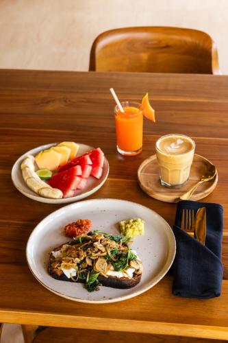a table with two plates of food and a plate of fruit at Uryah Hotel Lombok in Selong Belanak