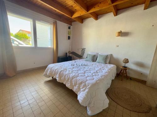 une chambre avec un grand lit blanc avec une fenêtre dans l'établissement Dans mon Verger - Agréable maison idéalement située, à Saint-Agnant