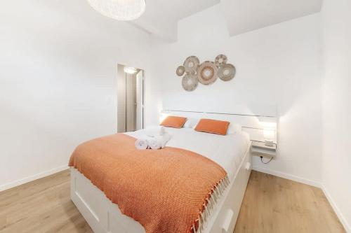 - une chambre blanche avec un grand lit et une couverture orange dans l'établissement Le Saint Martin, bel appartement de standing, à Rennes
