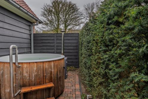a hot tub in a yard next to a fence at Villa Magnolia in Oostkapelle