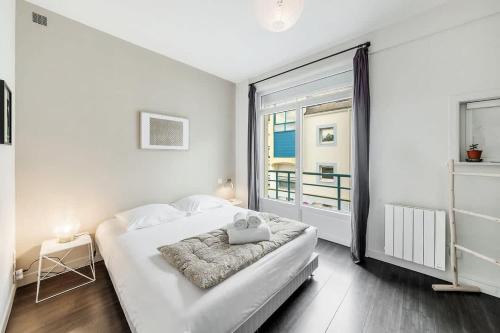 une chambre blanche avec un lit et une grande fenêtre dans l'établissement Le Calypso -proche du centre - Terrasse et parking, à Vannes
