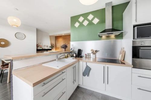 - une cuisine avec des placards blancs et un mur vert dans l'établissement Le Calypso -proche du centre - Terrasse et parking, à Vannes