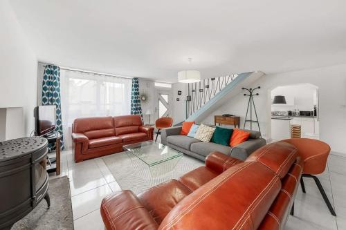 - un salon avec un canapé en cuir brun et un escalier dans l'établissement Maison des Flots, 3 chambres, jardin, proche plage, à Saint-Coulomb