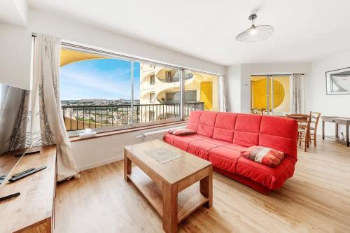 a living room with a red couch and a large window at Bellevue, appartement T2, terrasse & parking in Rennes