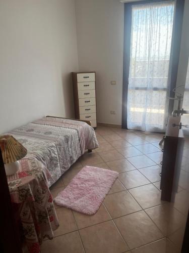 a bedroom with a bed and a dresser and a tiled floor at Casa vacanze La Gioia in Sestu