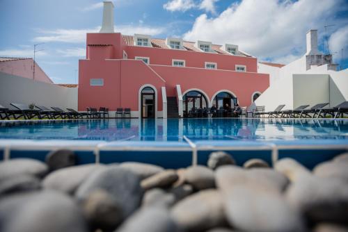 a swimming pool with a red building in the background at Charming Blue in Vila do Porto