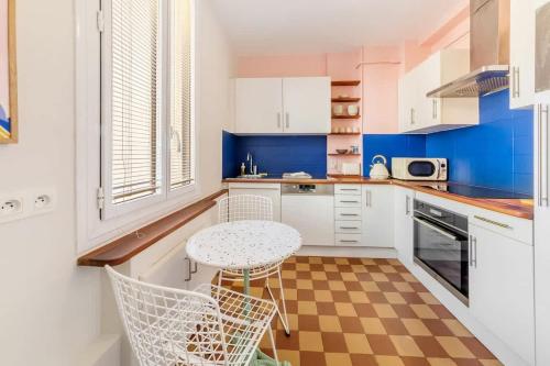 une cuisine avec des armoires blanches et une table et des chaises dans l'établissement Vadrouille - Proche Mail - Parking - 4 personnes, à Rennes