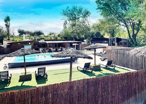 a swimming pool with chairs and umbrellas at Camping Le Val de Cesse in Mirepeisset
