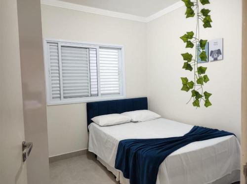 a bedroom with a bed with a blue headboard and a window at Casa aconchegante no interior in Boituva