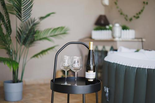 a bottle of wine and two wine glasses on a stand at Villa ElSi, Where Relaxation and Elegance Meet in Valenzano