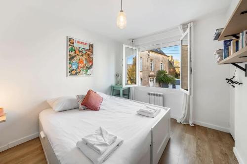 une chambre blanche avec un grand lit et une fenêtre dans l'établissement Le Cerf-Volant, joli 2 chambres, parking, à Saint-Malo