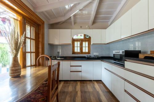 a kitchen with white cabinets and a wooden floor at Priory Cottage Heritage Haven in Nainital