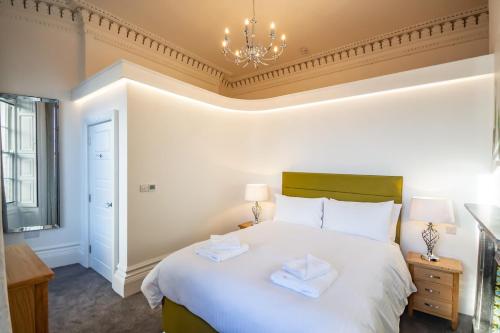 a bedroom with a white bed and a chandelier at Luxury 1 bedroom ground floor apartment in Plymouth
