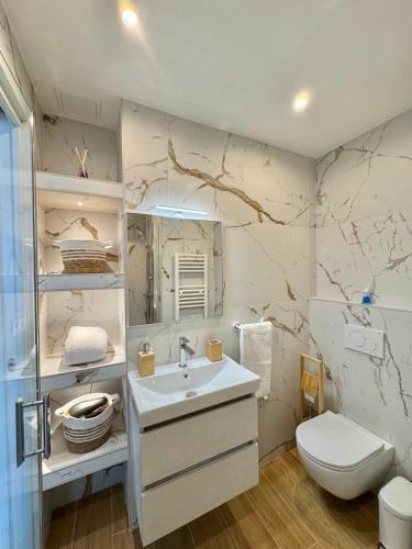 une salle de bain blanche avec un lavabo et des toilettes dans l'établissement Casa Sud Menton Appartement rénové et moderne en front de mer à Menton, terrasse, cuisine équipée, climatisé, WiFi et Netflix, à Menton