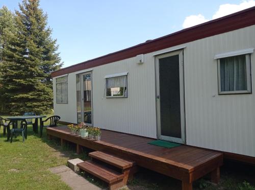 a house with a wooden deck next to a table at Domek kempingowy Przy Siole Budy in Budy