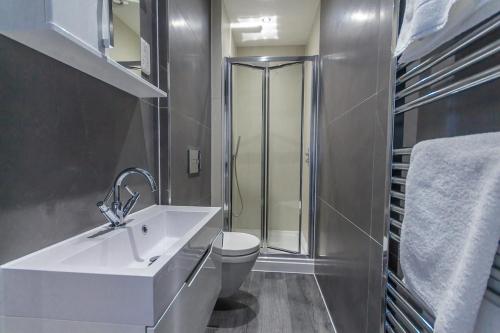 a bathroom with a sink and a toilet and a shower at Luxury 1 bedroom top floor apartment in Plymouth
