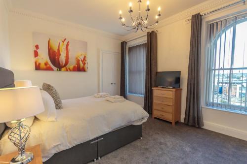 a bedroom with a bed and a television and a chandelier at Luxury 1 bedroom top floor apartment in Plymouth