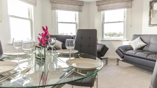 a living room with a glass table with wine glasses at The Crows Nest Apartment in Plymouth