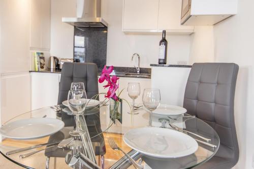 a glass table with three chairs and a flower on it at The Crows Nest Apartment in Plymouth