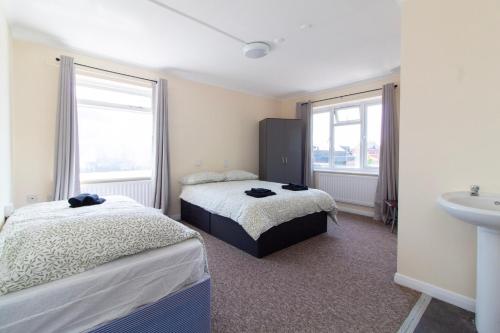 a bedroom with two beds and a sink and two windows at Brookvale Guest House Room 12 in Southampton