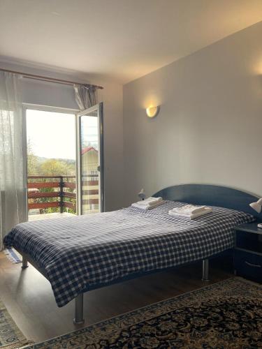 a bedroom with a bed with a checked blanket and a window at Vila Carpatina in Breaza