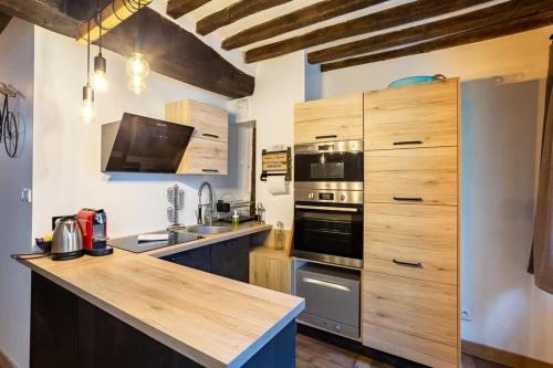 Una cocina con gabinetes de madera y encimera. en Le Jacobin, appartement de standing - Hyper centre, en Rennes
