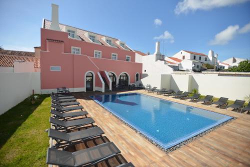 a swimming pool with lounge chairs and a house at Charming Blue in Vila do Porto