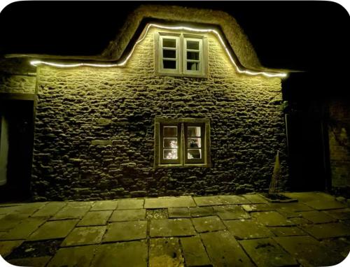 ein Gebäude mit einem Fenster mit Beleuchtung in der Unterkunft Thatch Cottage B&B in Lacock