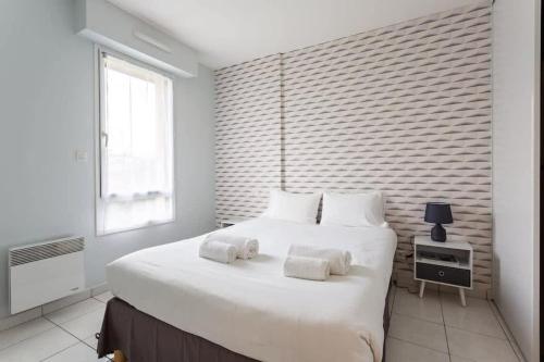 a bedroom with a large white bed with towels on it at L'Opale - Joli appartement avec jardin et garage in Dinard