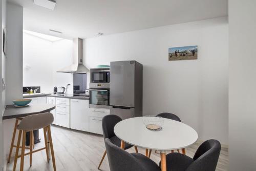 une cuisine blanche avec une table et des chaises blanches dans l'établissement Le Roazhon, hypercentre, moderne et spacieux, à Rennes