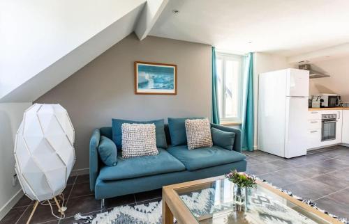 un salon avec un canapé bleu et une cuisine dans l'établissement Le George V - Beau 2 chambres - Coeur de St Servan, à Saint-Malo