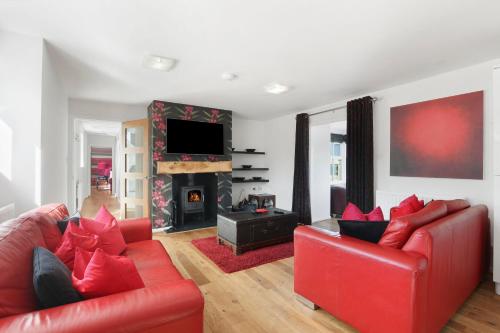 a living room with two red couches and a fireplace at Stable Cottage - North East Escapes in Bamburgh