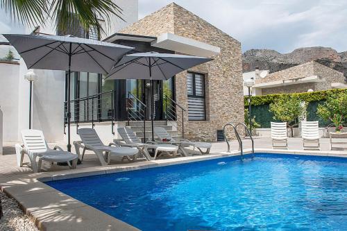 ポロップにあるModern villa with a private poolの家の隣にある椅子とパラソルのあるプール