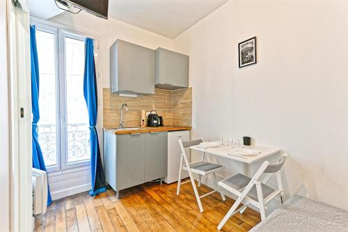 - une cuisine avec une table, une table et des chaises dans l'établissement Studio équipé dans le 18ème arrondissement, à Paris