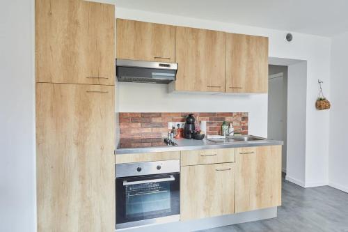 une cuisine avec des armoires en bois et un four à plaques de cuisson dans l'établissement L'Escale - appartement cosy 1 chambre - proche, à Rennes