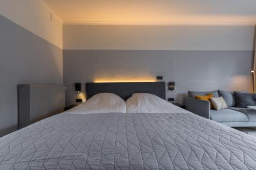 a bedroom with a large bed and a couch at Villa Magnolia in Oostkapelle