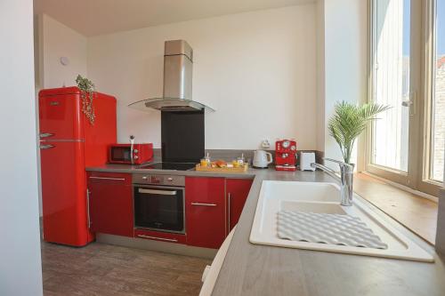 Il comprend une cuisine équipée de placards rouges et d'un réfrigérateur rouge. dans l'établissement La Manufacture Cosy, à Saint-Étienne