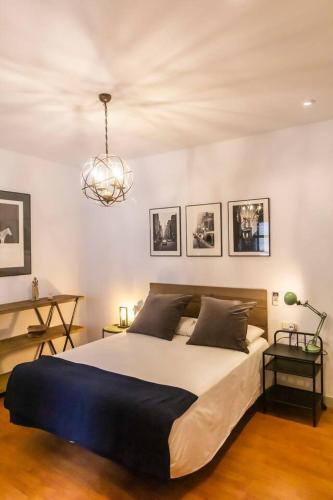 a bedroom with a large bed and a chandelier at SH La Casa del Capitán. Cerca de la catedral. in Cádiz