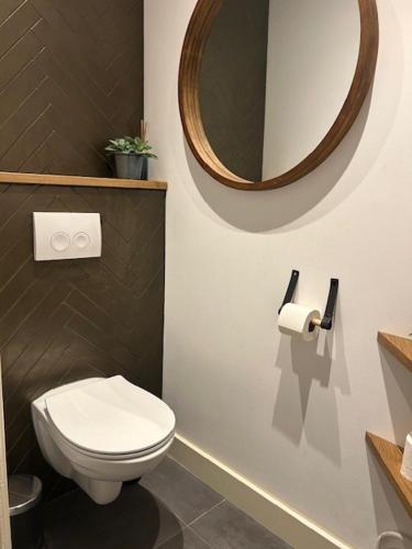 a bathroom with a white toilet and a mirror at De Boetz in The Hague