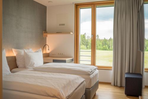a hotel room with two beds and a window at DEKRA Congresshotel Wart in Altensteig