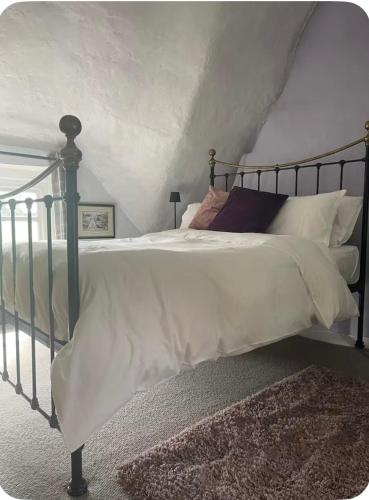a bedroom with a bed with white sheets and pillows at Thatch Cottage B&B in Lacock