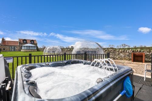a hot tub on a patio with two domes at Stable Cottage - North East Escapes in Bamburgh