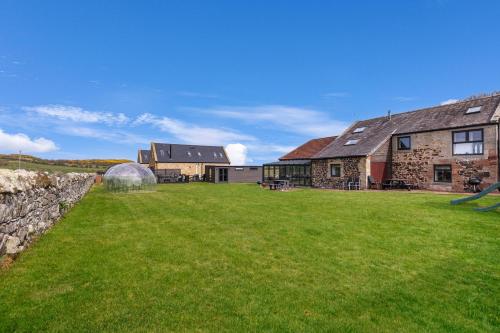 a large yard in front of a stone house at Stable Cottage - North East Escapes in Bamburgh