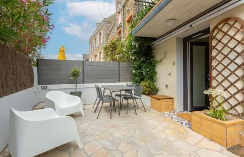 un patio avec une table et des chaises sur un patio dans l'établissement Saint Alexandre - Jolie maison atypique -Terrasse, à Dinard