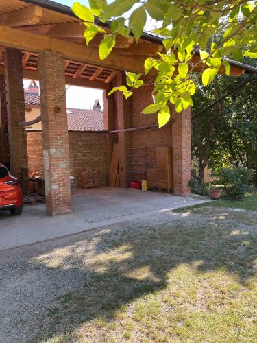 a brick house with a patio with a wooden roof at Appartamento Via Piane Azeglio in Azeglio