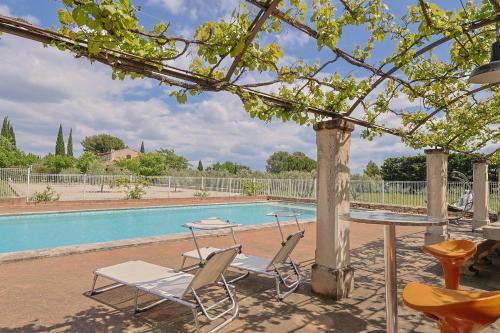 - une table et des chaises à côté de la piscine dans l'établissement Le Petit Nid, à Saint-Rémy-de-Provence