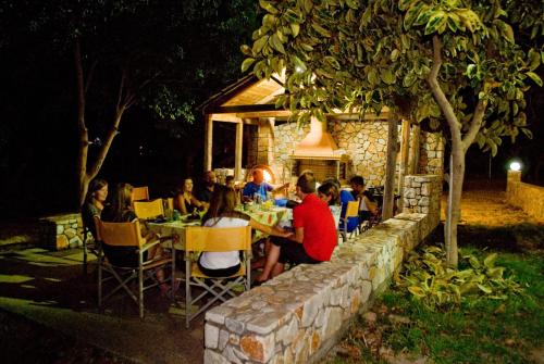 a group of people sitting at a table at night at Electra Studios in Palaiochóra
